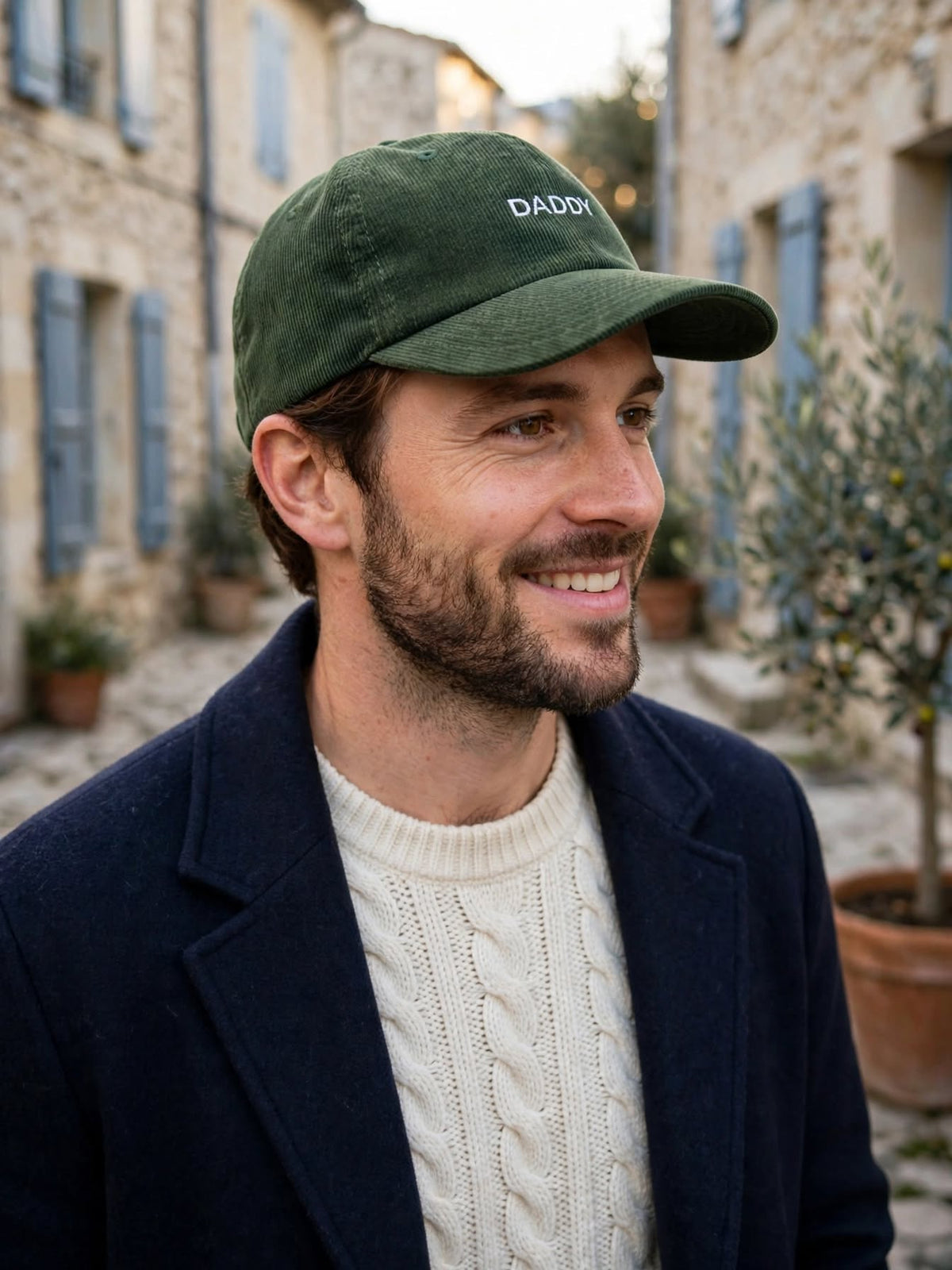 Homme portant la casquette en velours côtelé vert sapin brodée Daddy dans une ruelle de village provençal
