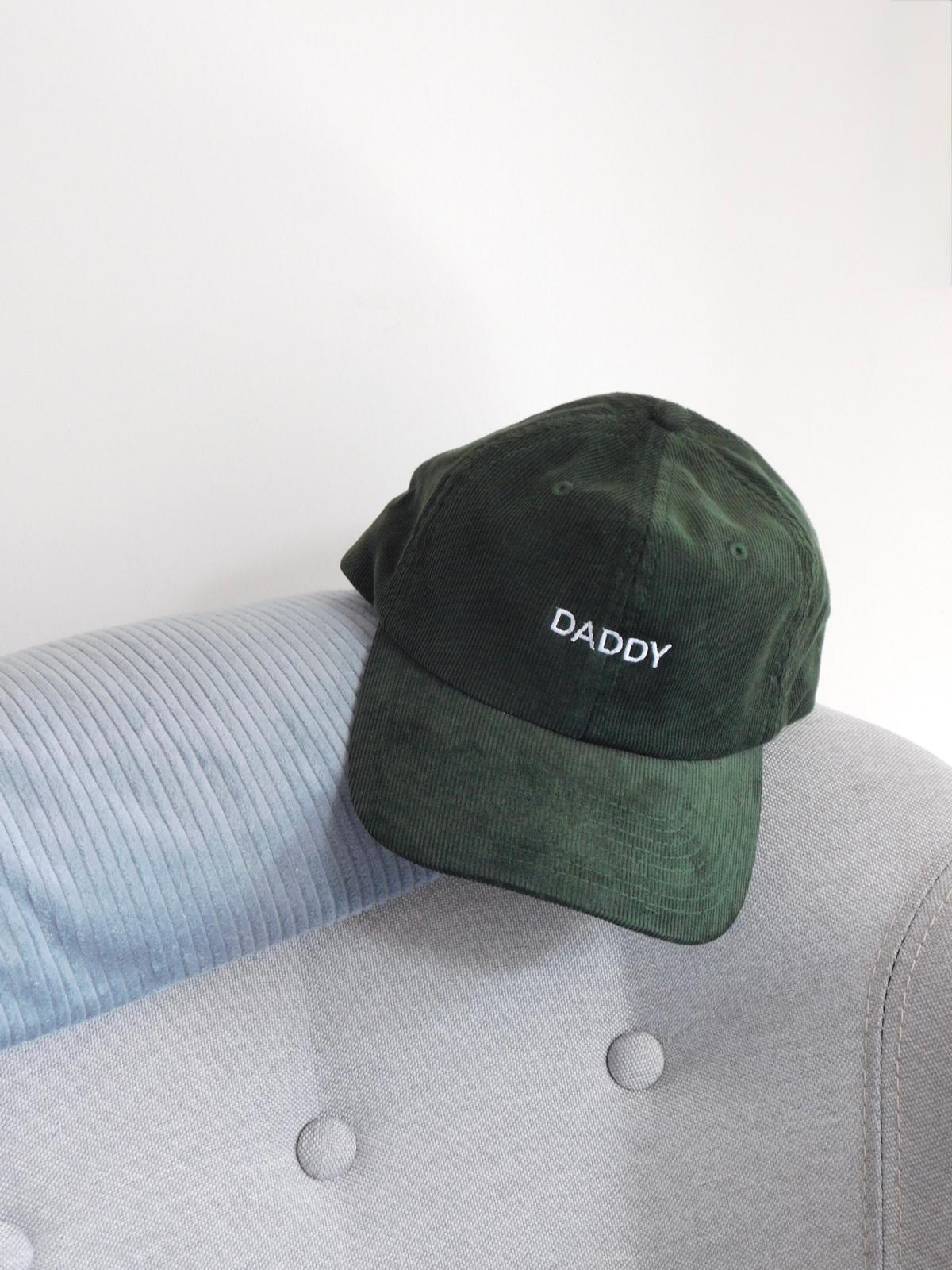 Casquette en velours côtelé vert sapin brodée Daddy, cadeau pour papa, posée sur un fauteuil gris