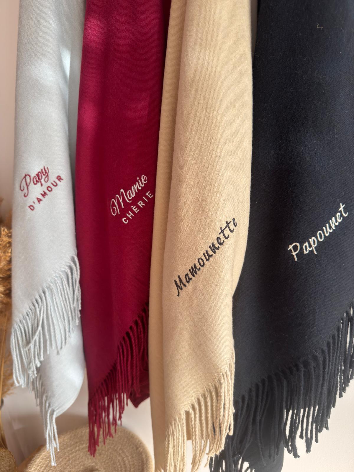 Écharpes brodées Papy d’amour gris clair, Mamie chérie bordeaux, Mamounette beige et Papounet noire suspendues à l’atelier