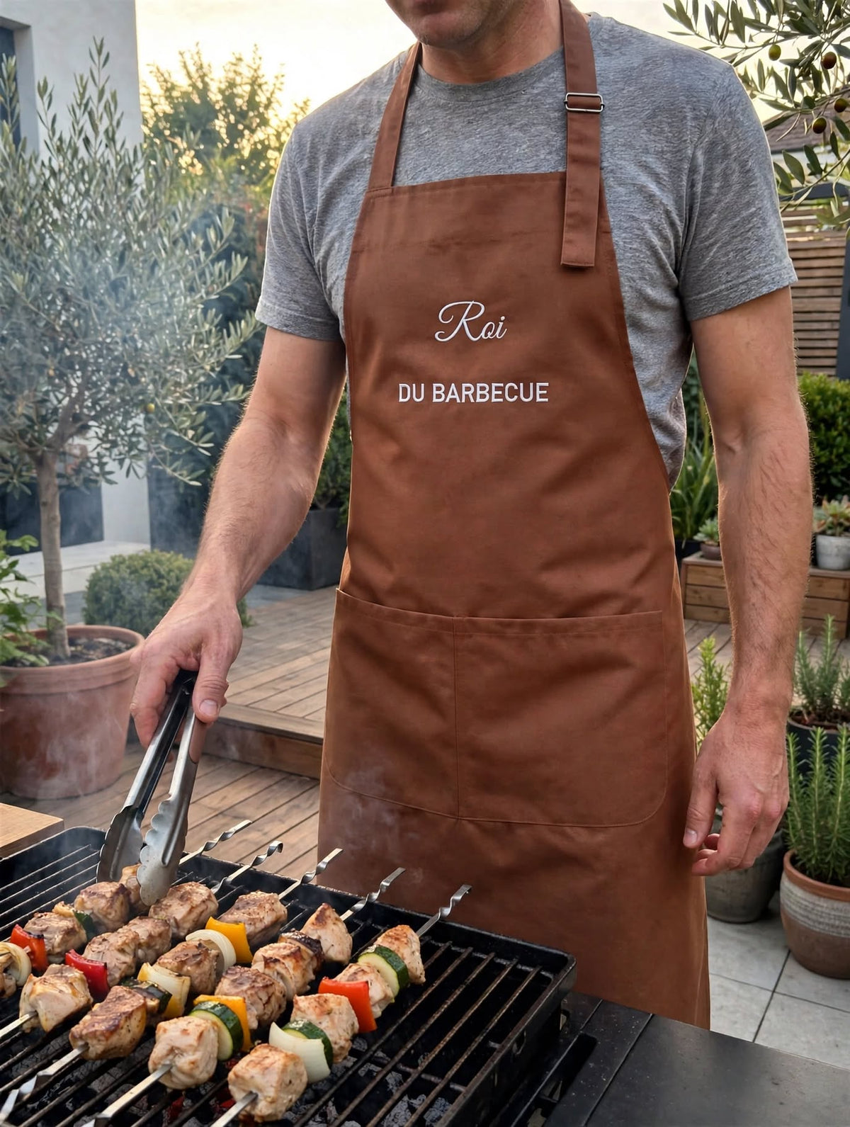 Tablier marron clair brodé Roi du barbecue porté devant le barbecue