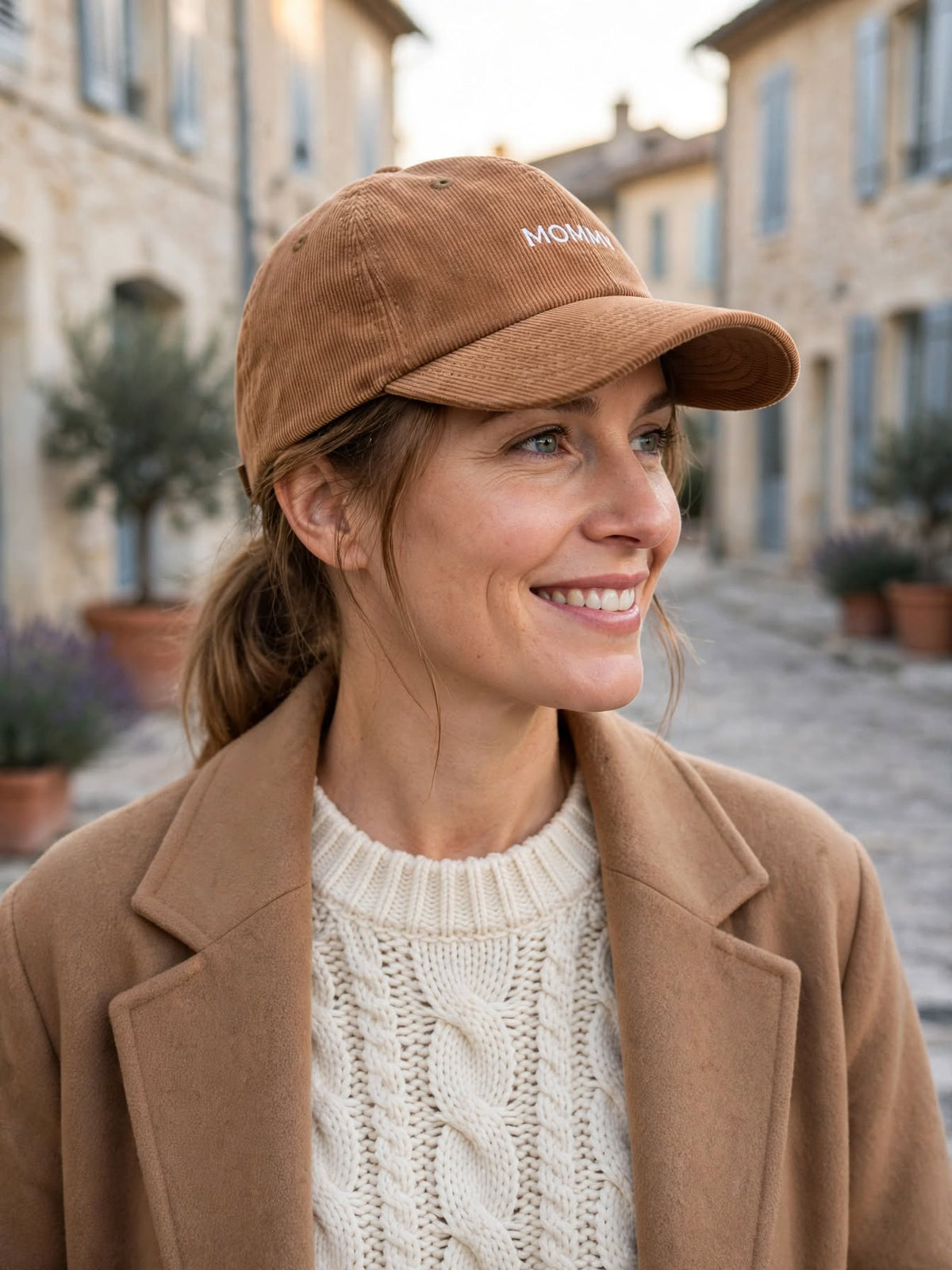 Femme portant la casquette en velours côtelé marron brodée Mommy dans une rue de village provençal