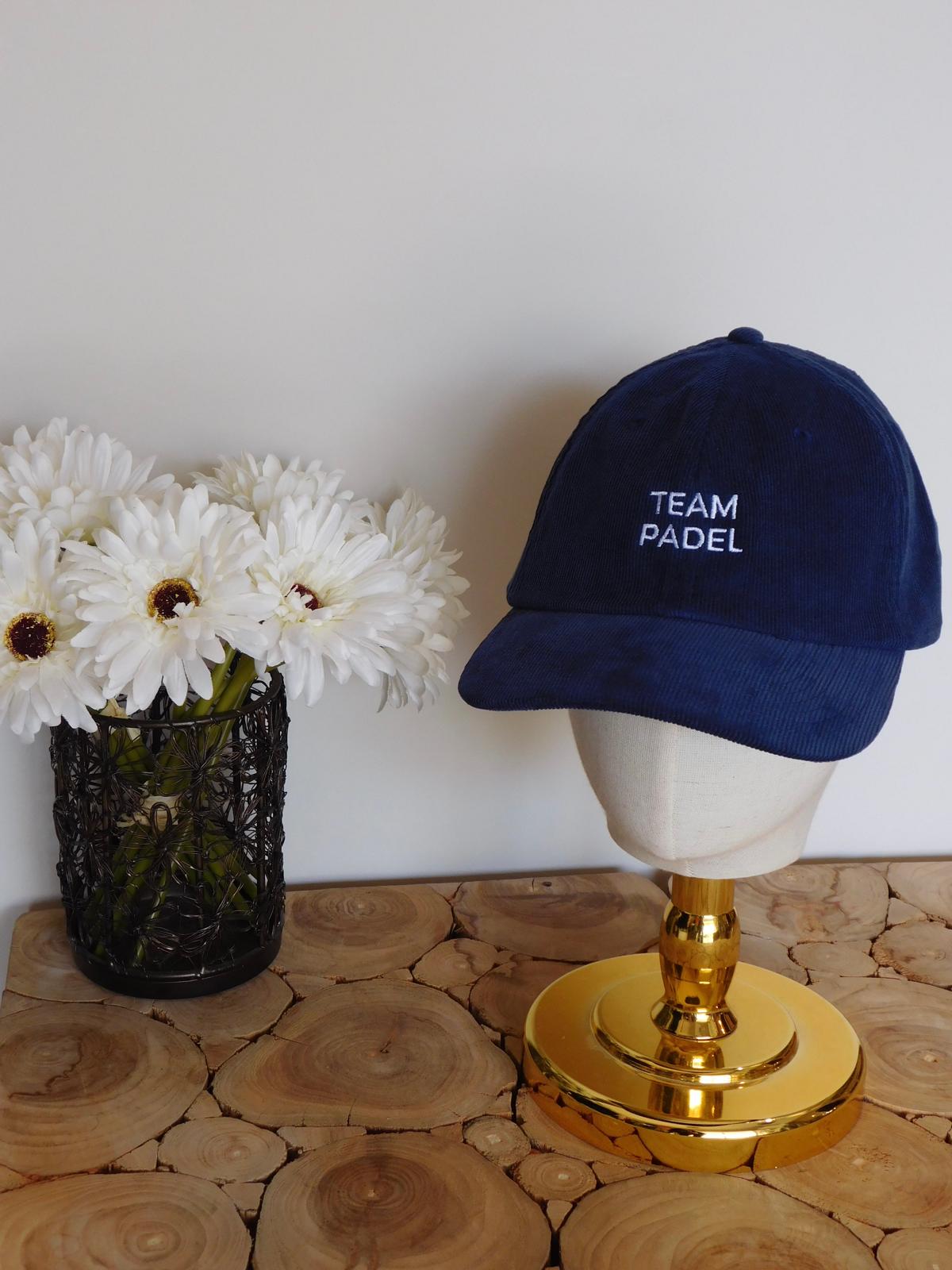 Casquette en velours côtelé bleu marine brodée Team Padel en fil blanc, sur une tête de présentation dorée
